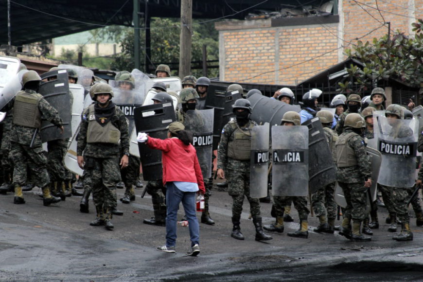 una mujer con chaqueta roja se enfrenta a un montón de policías armados