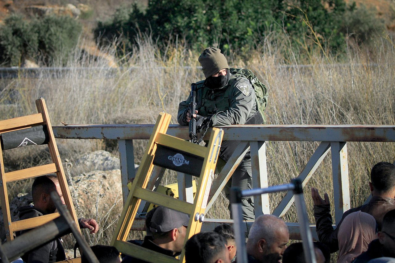 Soldados israelíes impiden a agricultores palestinos llegar a sus olivares a través de la puerta de acceso del asentamiento israelí de Elon Moreh, durante la temporada de cosecha en la aldea de Salem, al este de Nablus, Cisjordania ocupada, el 27 de noviembre de 2024. (Nasser Ishtayeh/Flash90)