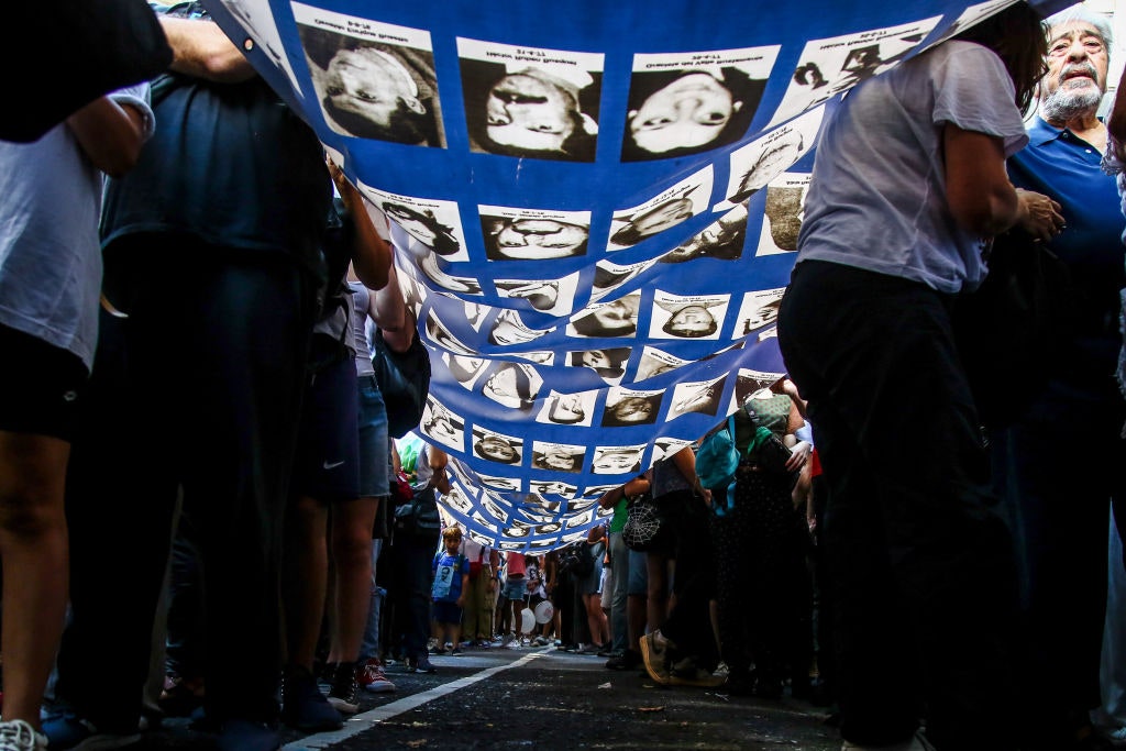 Manifestantes sostienen una manta con retratos de personas desaparecidas víctimas de la última dictadura militar de...