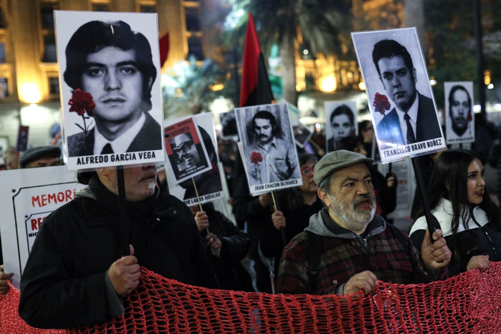 Personas marchan con retratos de detenidos desaparecidos de la dictadura de Augusto Pinochet en el Día Internacional de...